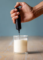 Tea Squared handheld milk frother being used in a glass of milk